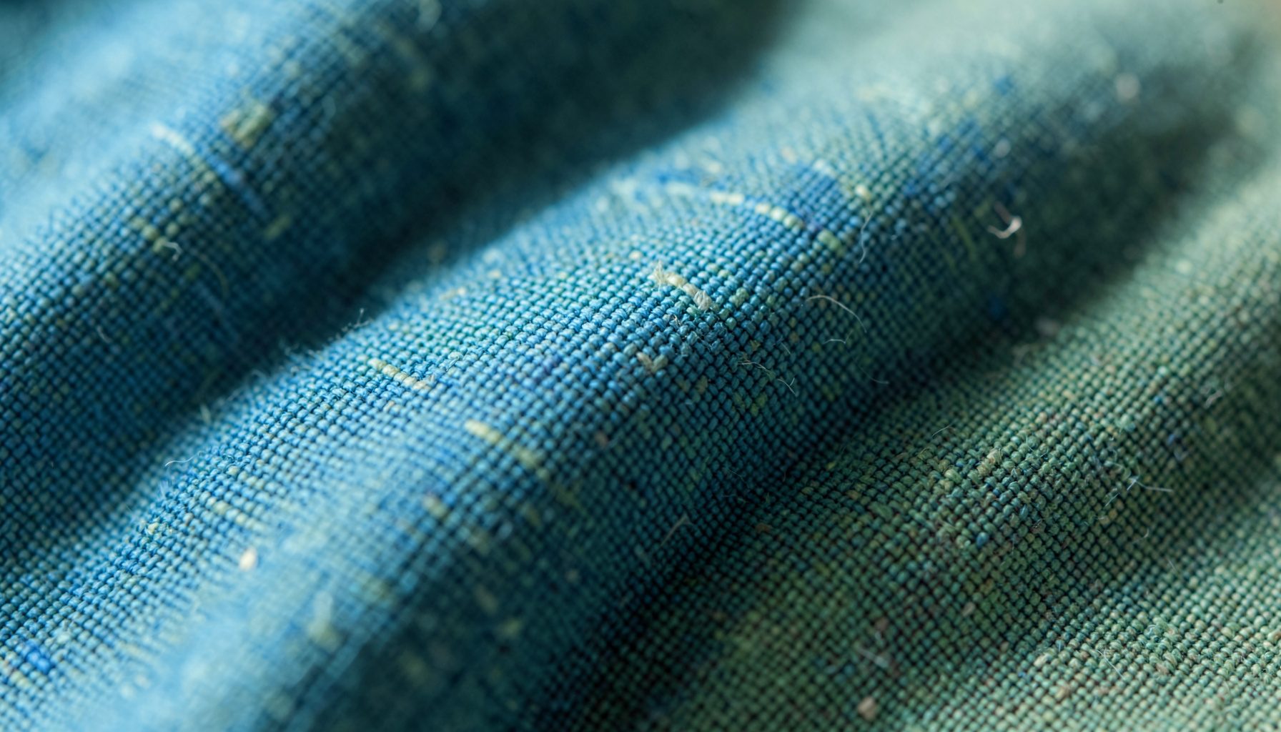 Extreme close-up photograph of tightly woven linen fabric in muted teal and sage green tones, soft natural light, calm professional mood