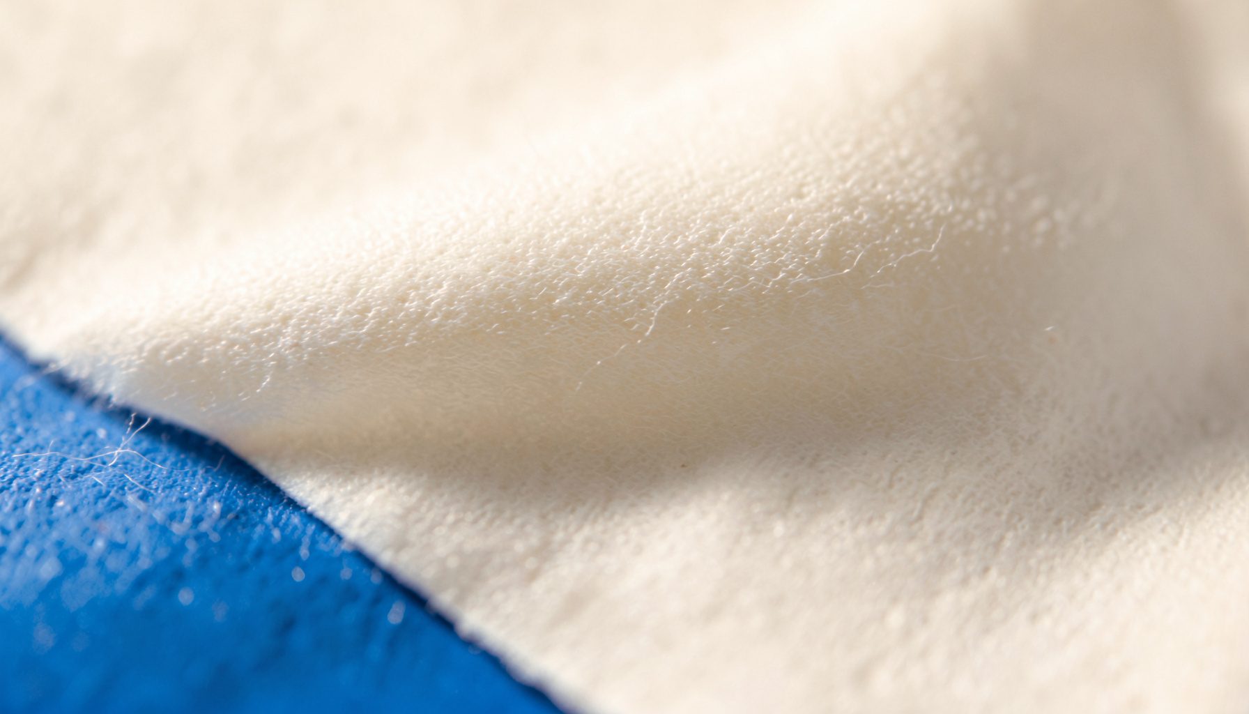Extreme close-up photograph of smooth cotton paper in warm off-white with a soft shadow, clean and minimal mood